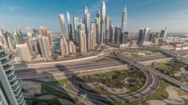 Dubai Marina karayolu kavşağı spagetti kavşağı zaman dilimi. Arka planda uzun gölgeler olan en uzun gökdelenler. JLT bölgesinin hava üst görüntüsü