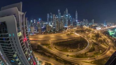 Dubai Marina karayolu kavşağı spagetti kavşağı tüm gece boyunca ışıklar kapalıyken. Arka planda en uzun gökdelenler aydınlatılıyor. JLT bölgesinden havadan panoramik görüntü.