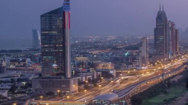 Dubai 'deki Şeyh Zayed Yolu' nun gece gündüz aydınlatma kuleleri olan hava görüntüsü. Metro istasyonlu bir otoyolda gökdelenler ve trafik