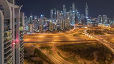 Dubai Marina karayolu kavşağındaki panorama spagetti kavşağı gece saat dilimi. Arka planında ışık olan en uzun gökdelenler. JLT bölgesinden hava üst görünümü.