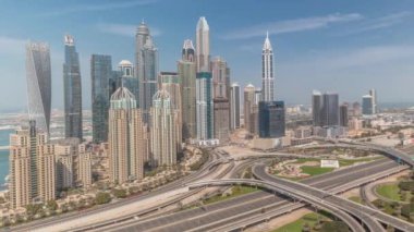 Dubai Marina karayolu kavşağındaki panorama spagetti kavşağı tüm gün boyunca devam etti. Arka planda hızla hareket eden gölgeli en uzun gökdelenler. JLT bölgesinden hava görüntüsü. Bulutlu gökyüzü