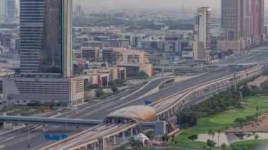Dubai 'deki Sheikh Zayed Yolu' nun zaman ayarlı hava görüntüsü. Sabah güneş doğduktan sonra metro istasyonu olan bir otoyolda gökdelenler ve trafik.