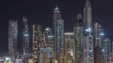 Dubai Marina 'nın gökdelenleri tüm gece boyunca parlayan ve yanıp sönen pencereli en yüksek konutlu binalar. JLT bölgesinden hava üst görünümü