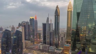 Dubai 'nin finans merkezi. Lüks gökdelenler, gece gündüz geçiş zamanları, Dubai, Birleşik Arap Emirlikleri. Otoparkı ve çatısı olan hava manzarası