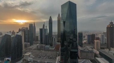 Dubai 'nin finans merkezi üzerinde gün batımı lüks gökdelenler zaman çizelgesi, Dubai, Birleşik Arap Emirlikleri. Turuncu gökyüzü ve büyük otoparkın etrafında kuleler olan hava panoramik manzarası.