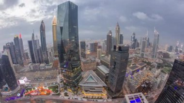 Gün batımından sonra Dubai 'deki finans merkezindeki gökdelenlerin panoramasında trafik günden geceye geçiş zamanlarında. Bulutlu gökyüzü ile yukarıdan hava görüntüsü
