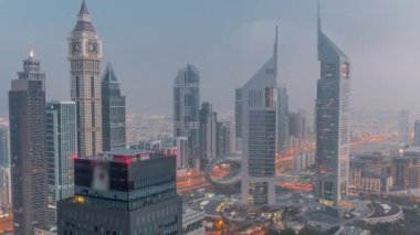 Sheikh Zayed Yolu 'ndaki gökdelenler ve Dubai, BAE' deki gece gündüz geçiş zamanları. Finansal merkez hava manzaralı aydınlık kuleler. Güneş doğmadan önce sisli hava