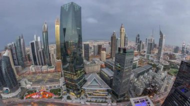 Dubai 'deki finans bölgesi iş merkezindeki gelecekçi gökdelenlerin panoraması. Gece gündüz yol trafiği geçiş zamanı. Güneş doğarken yukarıdan aydınlatma kuleleri ile gökyüzü görüntüsü