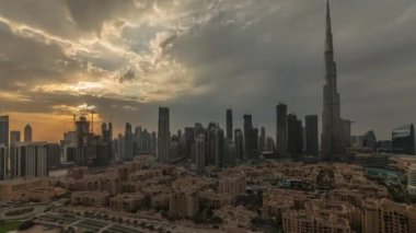 Dubai şehir merkezinde gün batımı, Dubai 'deki en uzun gökdelen ve diğer kule manzaralı Birleşik Arap Emirlikleri. Işık ışınları ve bulutlu turuncu gökyüzü