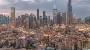 Dubai Şehir Merkezi 'nden gece geçişi, Dubai' deki Birleşik Arap Emirlikleri 'nde gün batımından sonra en yüksek gökdelen ve eski kasaba manzarası çevresindeki diğer kulelerle gerçekleşiyor. Işıklar yanıyor..