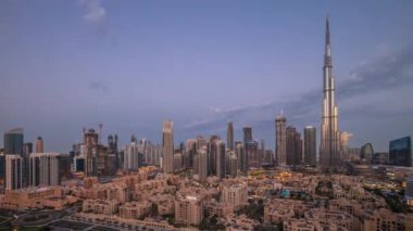 Dubai Şehir Merkezi 'nden gece gündüz geçiş zamanı en yüksek gökdelen ve diğer kule manzaralı gündoğumunda Birleşik Arap Emirlikleri. Eski şehrin geleneksel evleri ve pembeler