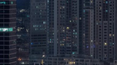 Modern ofisteki büyük parlayan pencereler ve konut binaları gece saatlerine göre ayarlanıyor, pencereler ışık saçıyor. Sokakta trafik vardı.