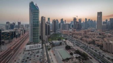 Dubais iş yeri kulelerinin panoramik görüntüsü hava gününden geceye geçiş zamanı. Gün batımından sonra inşaat halindeki bazı gökdelenlerin ve yeni binaların çatı manzarası