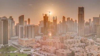 Dubais iş hangarı kuleleri, gün batımında hava saatinde. Bazı gökdelenlerin çatı manzarası ve vinçlerle inşa edilmiş yeni kuleler. Işıklı turuncu gökyüzü