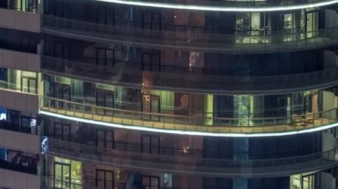 Modern konut binalarındaki büyük parlayan pencereler geceleri zaman ayarlı, sıra sıra parlıyor. Görüntüyü kapat