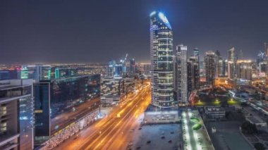 Dubais iş hangarı kuleleri panorama hava gece zaman çizelgesi. Bazı gökdelenlerin çatı manzarası ve inşaat halindeki yeni kuleler. Sokakta park ve trafik var.