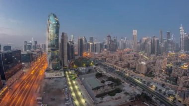 Dubais iş sahası kulelerinin panoraması gece gündüz geçiş zamanı. Güneş doğmadan önce inşa halindeki bazı gökdelenlerin ve yeni binaların çatı manzarası