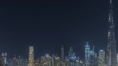 Panorama, Dubai Şehir Merkezi ve Business Bay gece zaman çizelgesini gösteriyor. Dubai 'deki en yüksek gökdelen ve diğer aydınlık kuleler, Birleşik Arap Emirlikleri manzaralı..