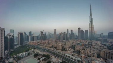 Dubai Şehir Merkezi 'nden gece gündüz geçiş zamanı güneş en yüksek gökdelenden ve güneş doğarken tepeden uzun gölgeli diğer kulelerden yansıyor. Birleşik Arap Emirlikleri. Geleneksel