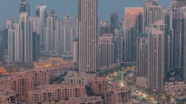 Dubai şehir merkezi ve iş sahasının aydınlatılmış mimarisiyle gece gündüz değişen şehirsel geçiş zamanı. Uzun gökdelenler ve kuleler. Yeni inşaat alanı.