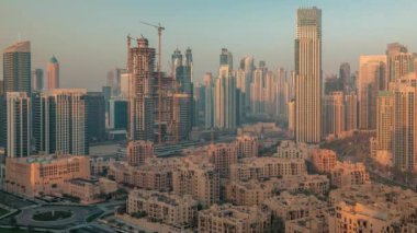 Dubais iş hangarı kuleleri havadan sabah saatleri. Güneş doğarken bazı gökdelenlerin çatısı ve inşaat halindeki yeni binaların manzarası