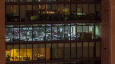 Modern ofis binalarındaki büyük parlayan pencereler geceleri zaman ayarlı, sıra sıra parlıyor. İşçiler içeride tadilat yapıyor.