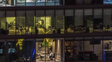 Modern ofis binalarındaki büyük parlayan pencereler geceleri zaman ayarlı, sıra sıra parlıyor. İçerideki bilgisayarlarda çalışanlar