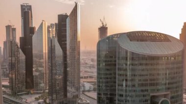 Dubai uluslararası finans merkezi gökdelenlerinin üzerinde gün batımı. Turuncu gökyüzü ve güneş kulelerin cam yüzeyinden yansıyor
