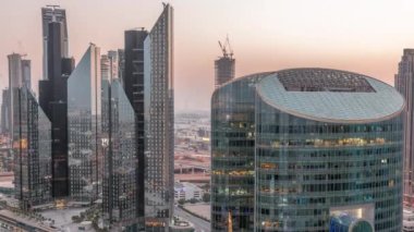 Dubai Uluslararası Finans Merkezi gökdelenleri hava gününden geceye geçiş zamanı. Yukarıdan parlayan pencere görünümlü aydınlık kuleler