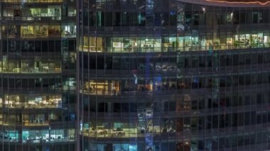 Modern ofisteki büyük parlayan pencereler ve konut binaları gece saatlerine göre ayarlanıyor, pencereler ışık saçıyor. Finans bölgesinde gökdelenler
