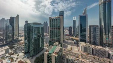 Dubai Uluslararası Finans Merkezi gökdelenleri bulutlu mavi gökyüzü ile panorama Gün batımına kadar tüm gün boyunca hava zaman aralığı. Gölgeler hızlı hareket ediyor ve güneş cam yüzeyden yansıyor.