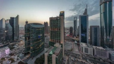 Dubai Uluslararası Finans Merkezi gökdelenleri hava gününden geceye geçiş zamanı. Aydınlatılmış kule manzaralı bir otoyol trafiği