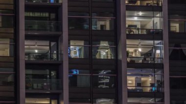 Modern ofisteki büyük parlayan pencereler ve konut binaları gece saatlerine göre ayarlanıyor, pencereler ışık saçıyor. Evde çalışma yeri