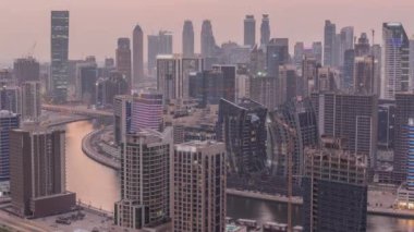 Dubai iş sahası kulelerinin modern mimarisine sahip Skyline 'dan geceye geçiş zamanı. Gün batımından sonra kanal ve şantiyeli hava manzarası