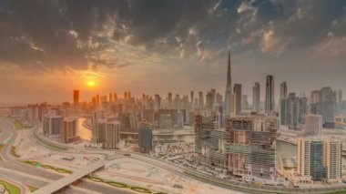 Dubai iş yeri kulelerinin modern mimarisi ve günbatımı saatinde şehir merkezinin Skyline 'ı. Kanal ve şantiyeli hava panoramik görüntüsü