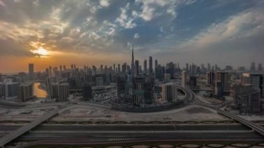 Dubai 'nin panoramik ufuk çizgisi üzerinde gün batımı iş sahası ve şehir merkezi zaman çizelgesi. Renkli bulutları ve ışık ışınları olan birçok modern gökdelenin havadan görünüşü. Birleşik Arap Emirlikleri.