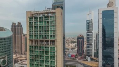 Panorama, Dubai Uluslararası Finans Merkezi 'nin gökdelenlerini geçit caddesindeki hava zaman aralığında gezinirken gösteriyor. Birçok ofis kulesi ve otoyol trafiği. Bulutlu gökyüzü