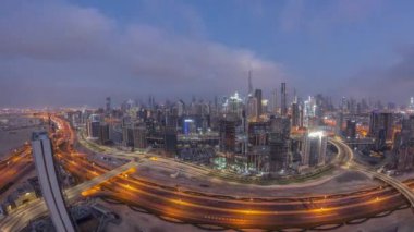 Dubai 'nin panoramik ufuk çizgisi. Gece gündüz iş sahası ve şehir merkezi geçiş zamanı. Gündoğumunda camdan yansıyan yansımalarla birçok modern gökdelenin gökyüzü geniş açılı görüntüsü