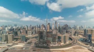 Dubai 'nin panoramik silueti, iş sahası ve şehir merkezi zaman çizelgesi. Uzun gölgeleri ve bulutlu mavi gökyüzü olan birçok modern gökdelenlerin havadan görünüşü. Birleşik Arap Emirlikleri.