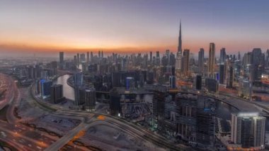 Dubai iş sahası ve şehir merkezindeki kulelerin modern mimarisi ile panoramik ufuk çizgisi günden geceye geçiş zamanı. Gün batımından sonra kanal ve şantiyeli hava manzarası