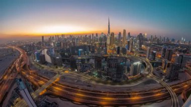 Dubai 'nin panoramik silueti, iş sahası ve şehir merkezi ile gündüz ve gece arasında. Günbatımından sonra Al Khail yolunda trafiği olan birçok modern gökdelenin geniş açılı görüntüsü.