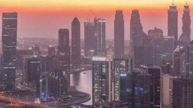 Dubai iş sahası kulelerinin modern mimarisine sahip Skyline 'dan geceye geçiş zamanı. Güneş battıktan sonra renkli gökyüzü ile kanal ve şantiyeli hava manzarası