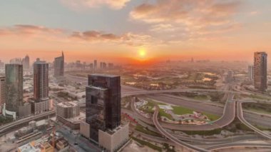 Medya şehri yakınlarındaki otoyol kavşağında gün doğumu ve Dubai marinasının arka planında Al Barsha tepeleri bölgesi. Kuleler ve gökdelenler sabahın erken saatlerinde golf sahası ve trafik