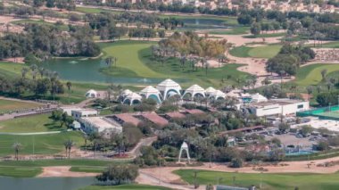 Golf sahasının havadan görünüşü yeşil çimenler ve göller, arkasındaki villalar zaman geçiyor. Avuçlar otoparkta. Dubai marina gökdeleninden en iyi manzara.