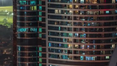 Gecenin geç saatlerinde ışıldayan ve yanıp sönen iç ışıkları olan yüksek katlı binadaki pencereler. Golf sahasının havadan görünüşü