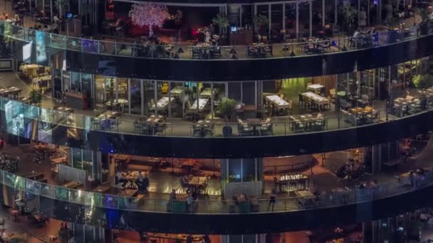 迪拜的码头和灯光明亮的大楼 每层空中夜间都有不同的餐厅 可以俯瞰全景 吃饭的时候 人们坐在桌旁休息 — 图库视频影像