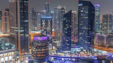 Dubai Marina Skyline ve JLT gökdelenleri tüm gece boyunca arka plan anteninde. Cam yüzeyi ve ışıkları sönen aydınlık kuleler.