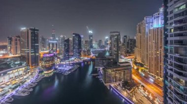 Dubai marinasına giden hava manzarası kanalın etrafındaki gökdelenleri aydınlatıyordu. Gece boyunca yüzen yatlar vardı ve ışıklar kapalıydı. Yat kulübünde beyaz tekneler var.