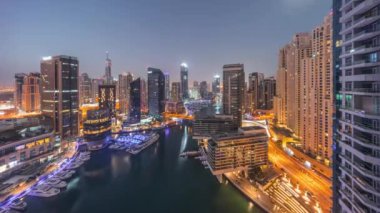 Dubai marinasının hava panoramik görüntüsü kanalın etrafındaki gökdelenleri gece gündüz yüzen yatlarla aydınlattı. Güneş doğmadan önce beyaz tekneler yat kulübüne park edilir.