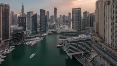 Havadan Dubai marina gökdelenleri ve kanalın etrafındaki JBR kuleleri ve gece gündüz yüzen botlarla geçiş zamanı. Günbatımından sonra beyaz tekneler yat kulübüne park edilir.